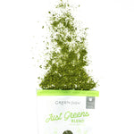 Green powder spilling out of a bag labeled 'Green Juju Just Greens Blend' on a white background