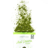 Green powder spilling out of a bag labeled 'Green Juju Just Greens Blend' on a white background