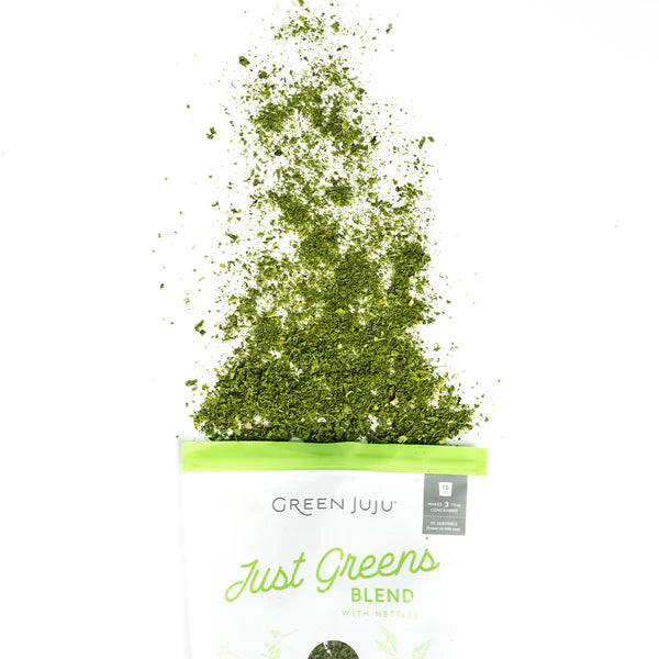 Green powder spilling out of a bag labeled 'Green Juju Just Greens Blend' on a white background