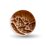 A round brown silicone baking mat featuring a relief design of mountains, trees, and a rising sun, shown on a clean white background with a soft drop shadow.