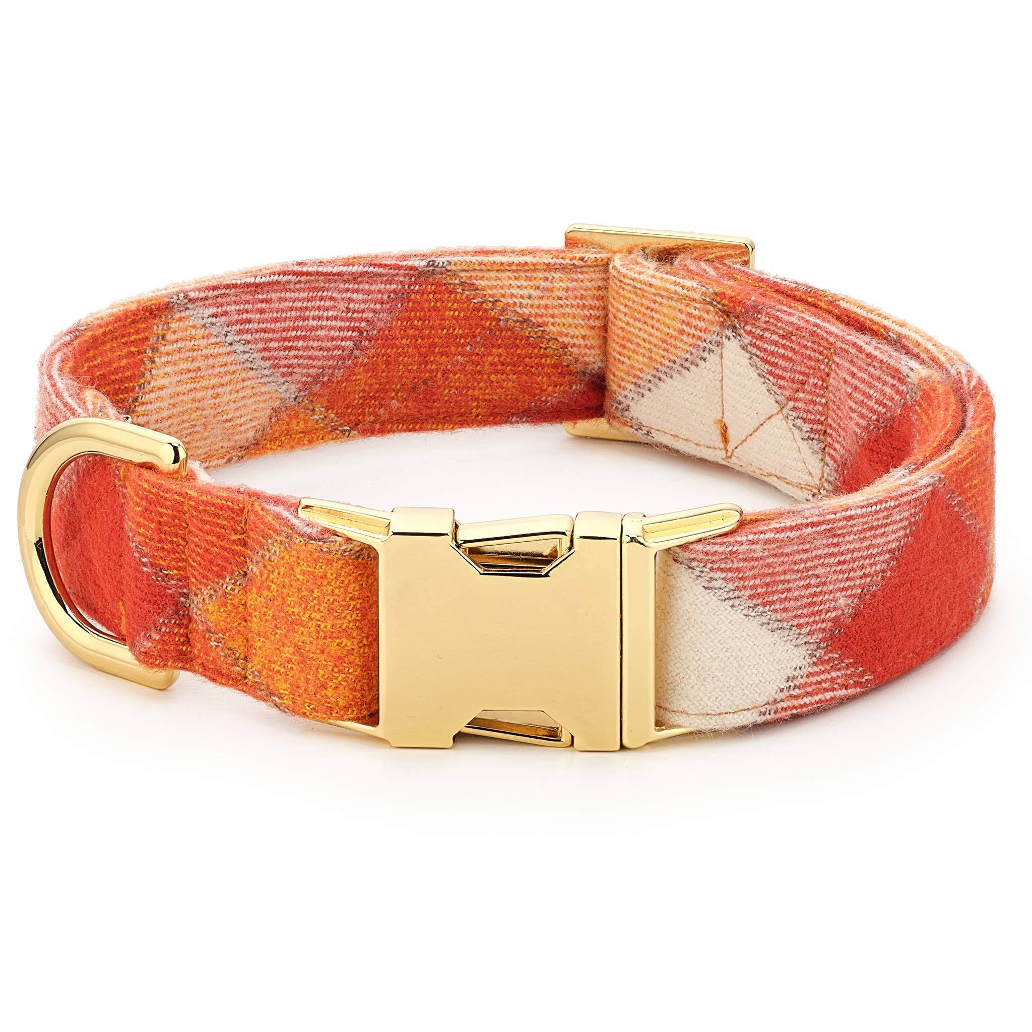 A woven fabric dog collar with a warm orange, red, and cream plaid pattern, featuring a polished gold-tone metal buckle and D-ring, shown on a clean white background.