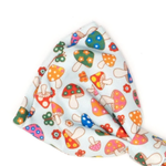 A light blue ribbed fabric accessory, likely a headband or hair tie, featuring a colorful pattern of cartoon mushrooms and small flowers in red, orange, green, blue, and pink.