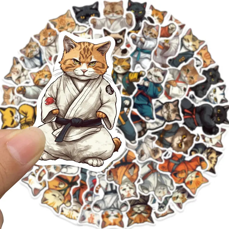 Sticker of a cat in a martial arts outfit held over a collection of similar cat-themed stickers.