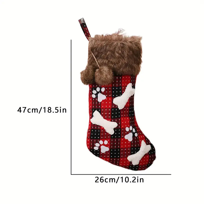 Dog Christmas stocking with paw prints and bones design, held by a brown plush dog toy, on a white background.