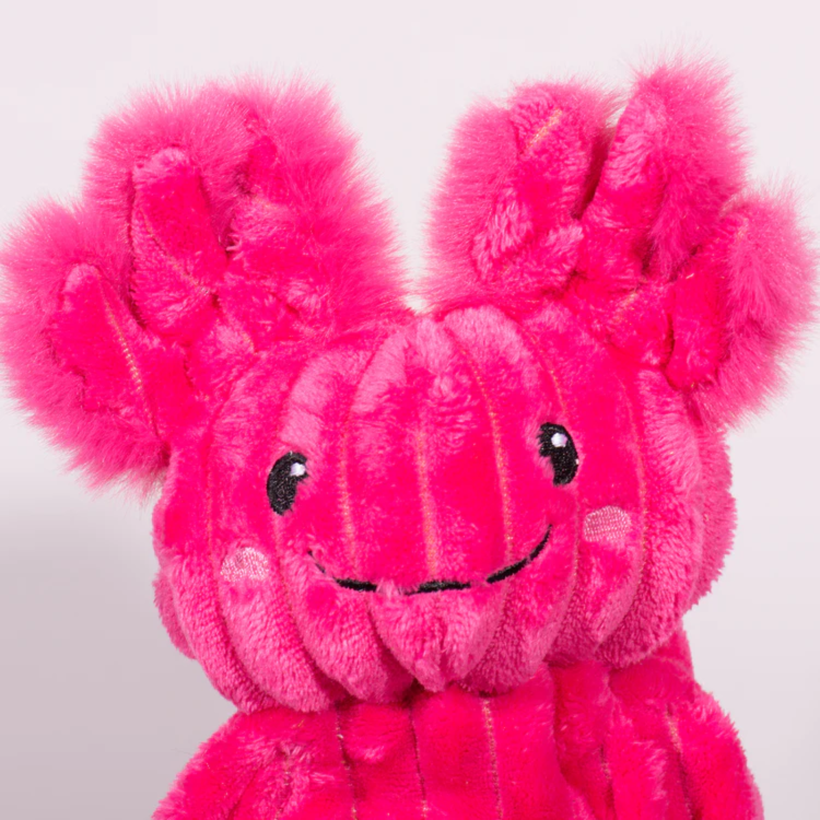 Pink plush toy with a smiling face on a white background