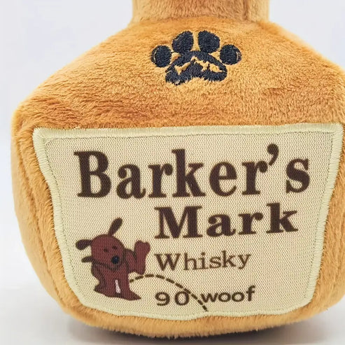 Plush toy resembling a bottle labeled 'Barker's Mark Whisky' with a paw print design.