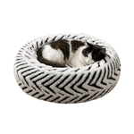 A plush round black and white pet bed with a black and white cat sleeping in the center.