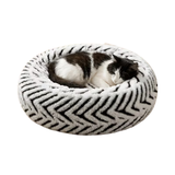 A plush round black and white pet bed with a black and white cat sleeping in the center.