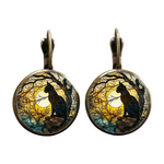 Pair of earrings with cat silhouette design against a moonlit sky.