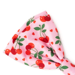 A pink grosgrain ribbon bow featuring a cherry and heart pattern, photographed on a clean white background.