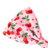 A pink grosgrain ribbon bow featuring a cherry and heart pattern, photographed on a clean white background.