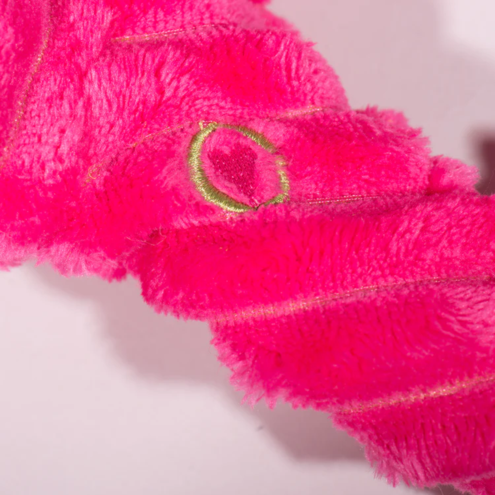 Close-up of a pink towel with a gold ring detail on a white background