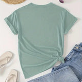 Mint green t-shirt with a knot detail, paired with denim jeans and a straw hat on a light background.