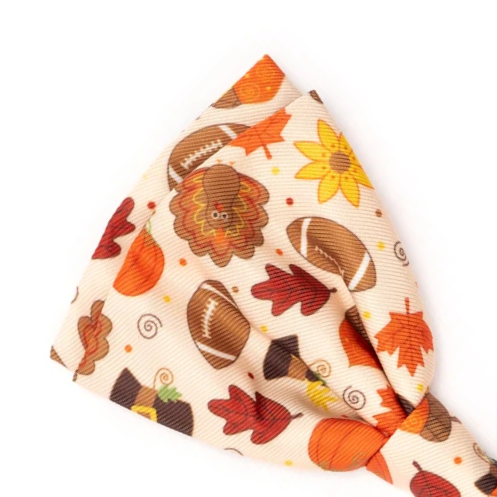 A folded fabric accessory, likely a bandana or pocket square, featuring a festive autumn pattern with footballs, pumpkins, leaves, and a turkey on a cream background.