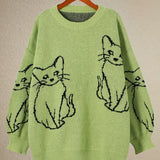 Green sweater with black cat illustrations on a beige background