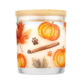 Candle with autumn-themed design featuring pumpkins, leaves, and a cinnamon stick on a white background.