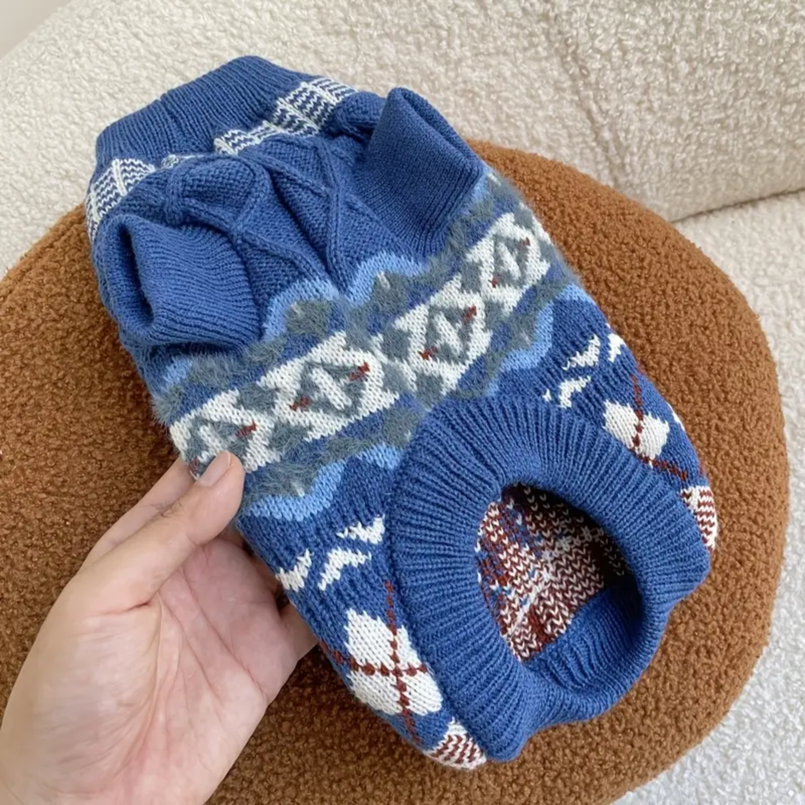 Blue patterned socks held by a hand on a brown surface