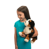 Girl holding a stuffed dog toy with a white, brown, and black pattern on a white background