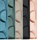 Four silicone ice cube trays with geometric patterns in different colors on a white background.