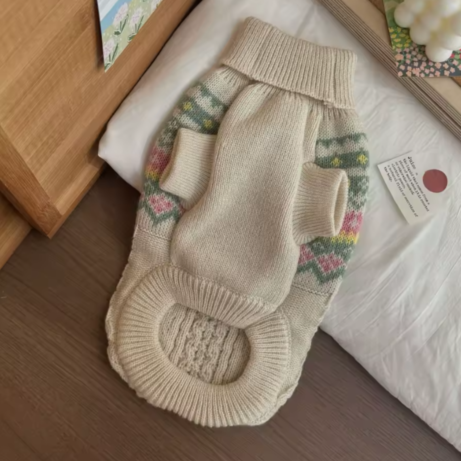 Knitted dog sweater with floral patterns on a wooden surface