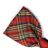 A close-up of a red tartan plaid fabric accessory, likely a pocket square or folded necktie, on a plain white background.