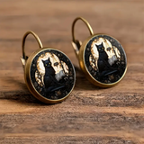 Pair of earrings with black cat design on a wooden surface