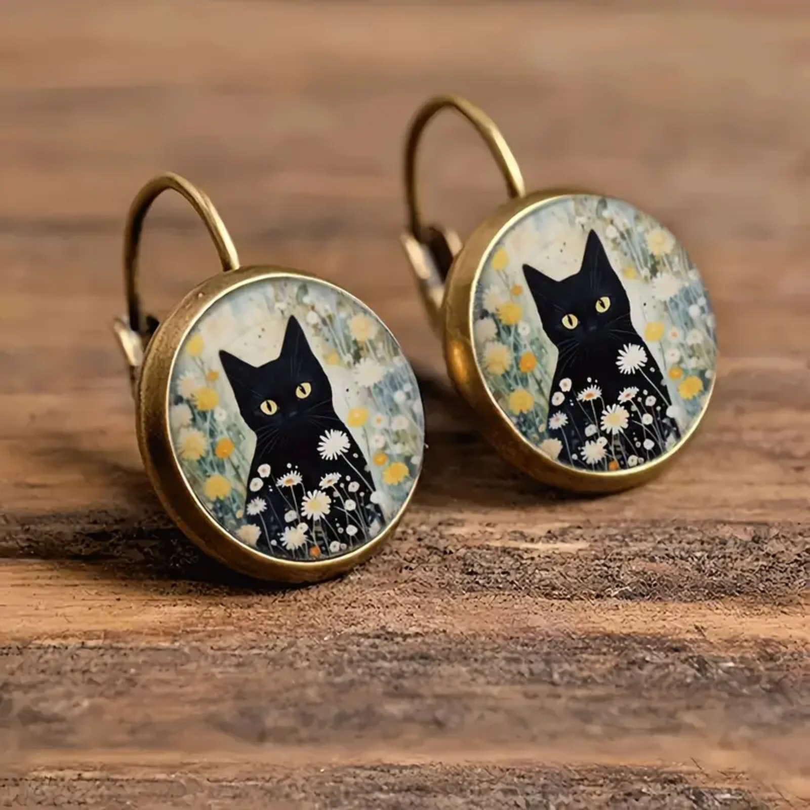 Pair of earrings with black cat design on a wooden surface