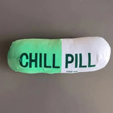 Pillow shaped like a green and white pill with 'CHILL PILL' text on a gray background
