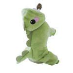 Green plush toy resembling a dragon on a white surface with a blurred background