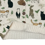 Patterned fabric with animal illustrations and a knitted blanket on top