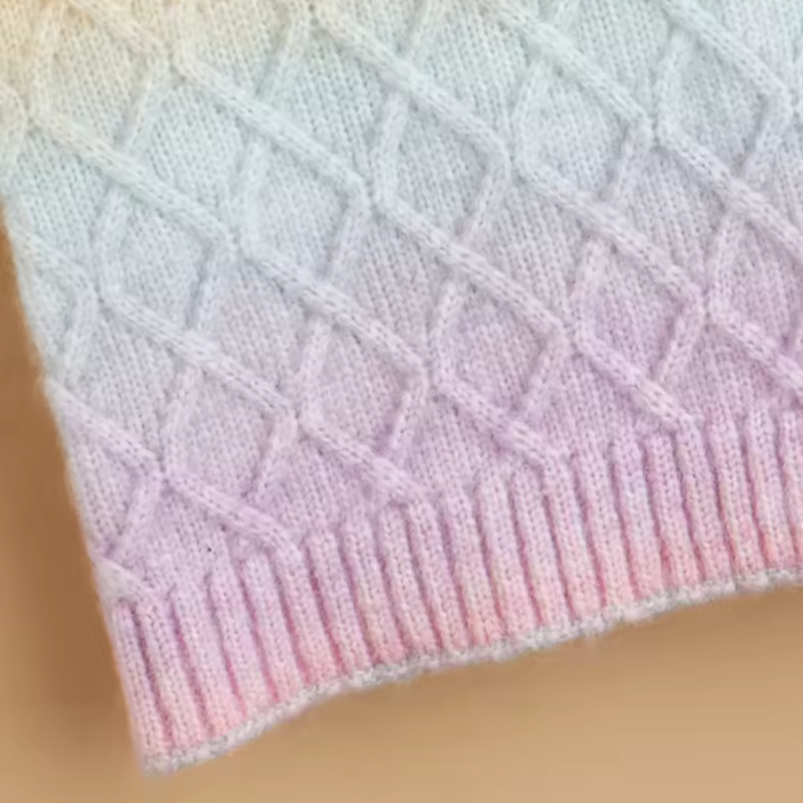 Close-up of a pastel pink and blue knitted fabric with a textured pattern.