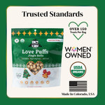 Package of Love Puffs Jingle Bells dog treats with branding and certification logos on a green background