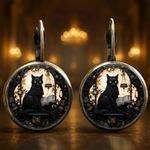 Pair of earrings with black cat design on a warm, blurred background