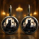 Pair of earrings with black cat design on a warm, blurred background