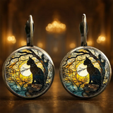 Pair of earrings with cat silhouette design against a moonlit tree background.