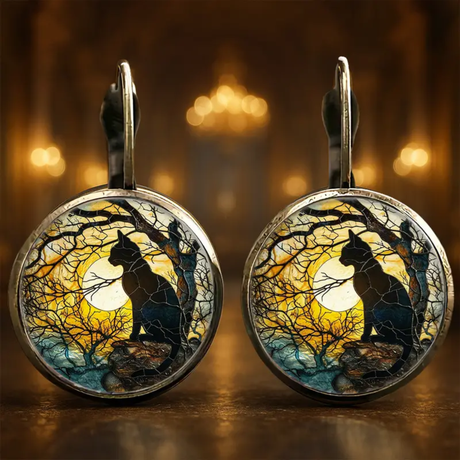 Pair of earrings with cat silhouette design against a moonlit tree background.