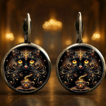 Pair of earrings with intricate designs of a black cat and coffee cup on a dark background.