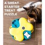 Dog playing with a yellow and blue treat puzzle toy on a wooden floor.