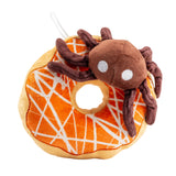 Plush toy resembling a spider on an orange donut with white patterns against a white background