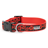 A red and black dog collar with a black and red poppy pattern, featuring a black plastic buckle, a silver metal ring, and a white brand label that reads 'WORTHY OF DANG'.