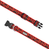 A red and black dog collar with a repeating poppy pattern, featuring black plastic quick-release buckles and a silver metal D-ring, shown on a plain white background.