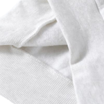 Close-up of a white ribbed knit fabric, showing the texture and folds of a garment or textile.