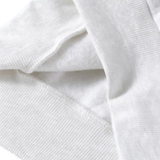 Close-up of a white ribbed knit fabric, showing the texture and folds of a garment or textile.