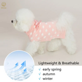 Small white dog wearing a pink polka dot outfit with text about clothing suitability for seasons.