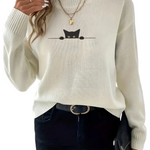 White sweater with a black cat design worn by a person on a white background