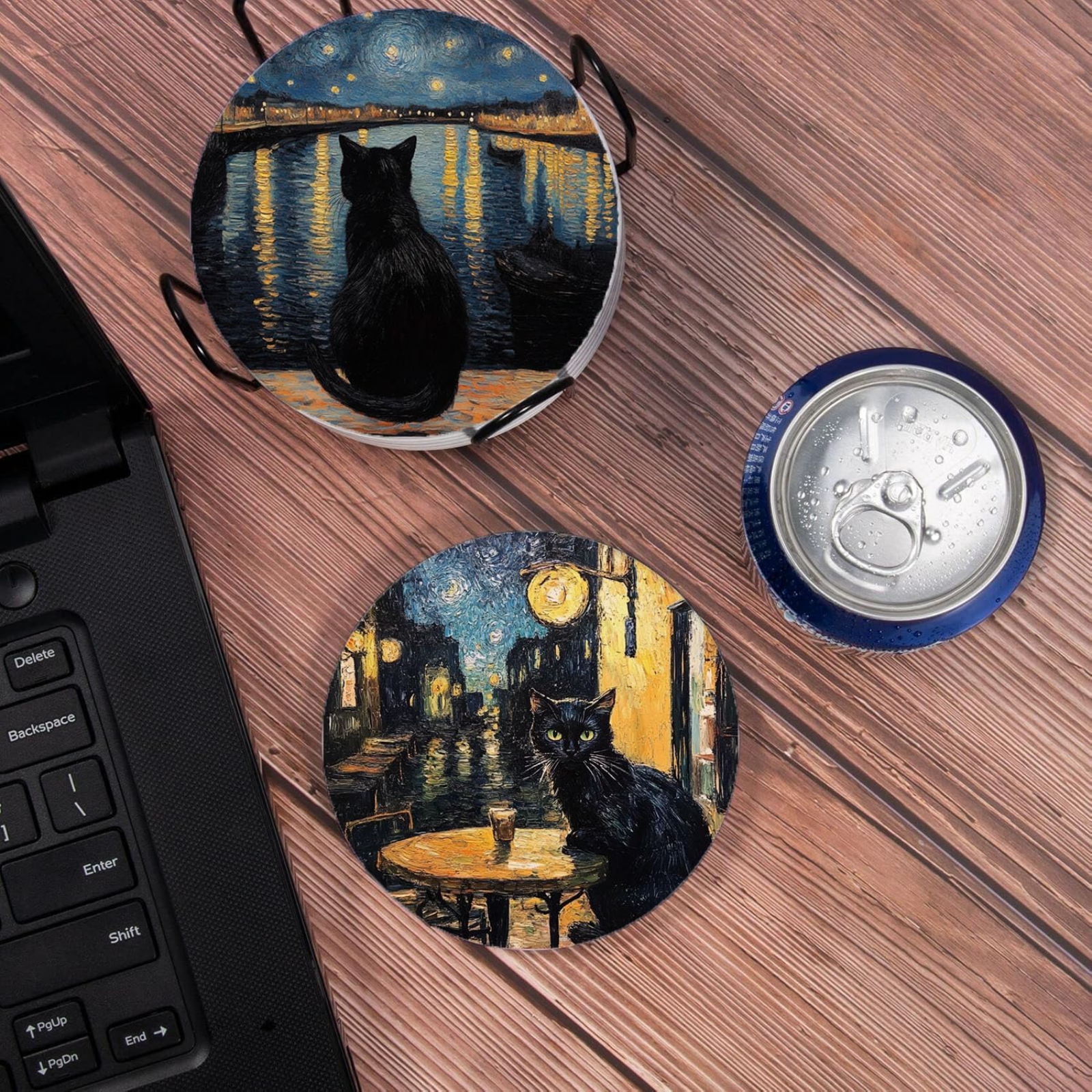 Two round coasters with black cat designs on a wooden surface next to a laptop.