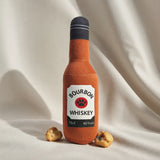 Toy bourbon whiskey bottle with a label on a beige fabric background