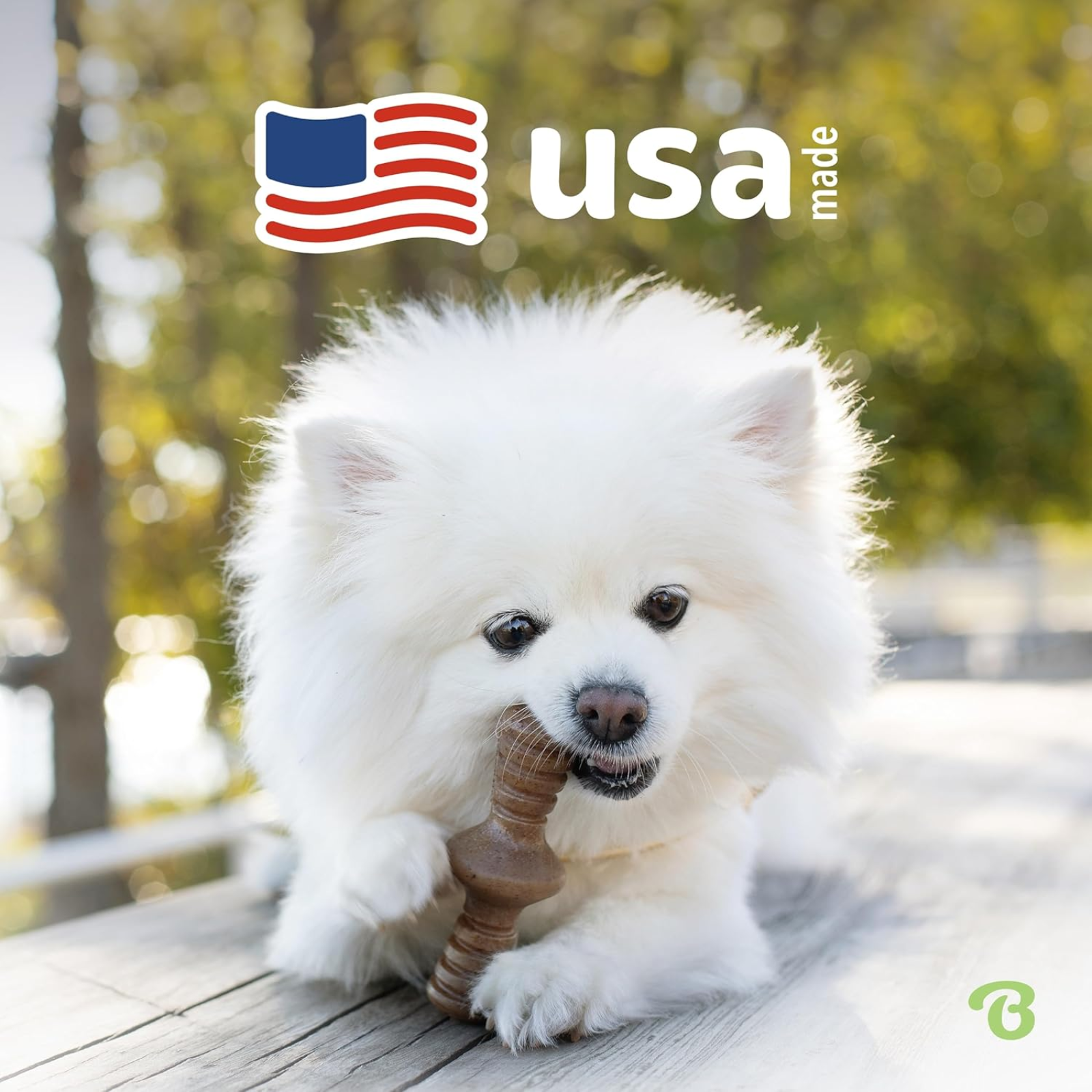 White dog playing with a wooden toy on a wooden deck, with 'USA Made' text and flag in the corner.