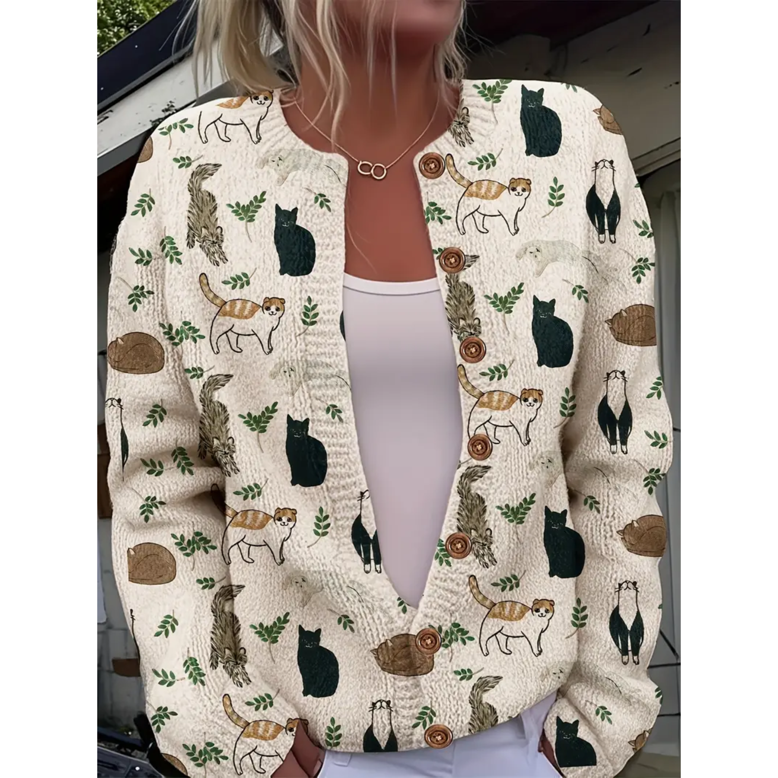 Cardigan with cat pattern worn by a person, with a blurred background