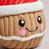 A close-up of a cupcake-shaped squishy toy with a textured tan body, white frosting, pink cheeks, and a red Santa hat, shown against a plain light background.